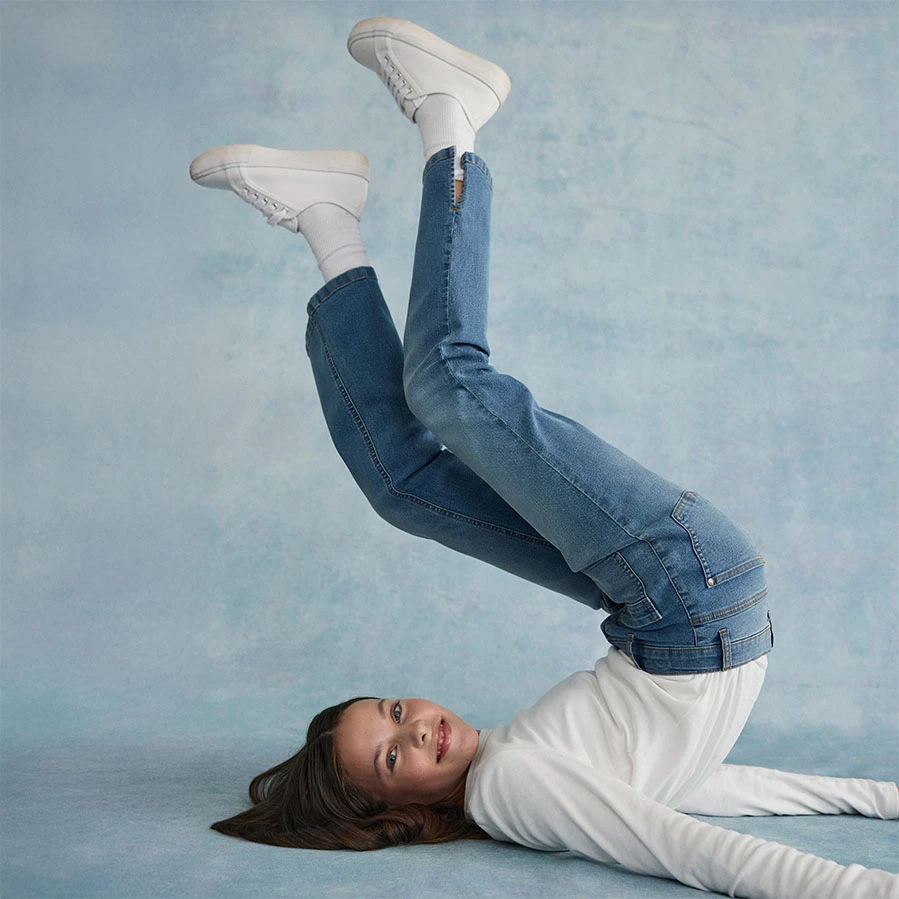 T‑shirt blanc à manches longues et au style épuré, associé à un jean décontracté et des baskets blanches.