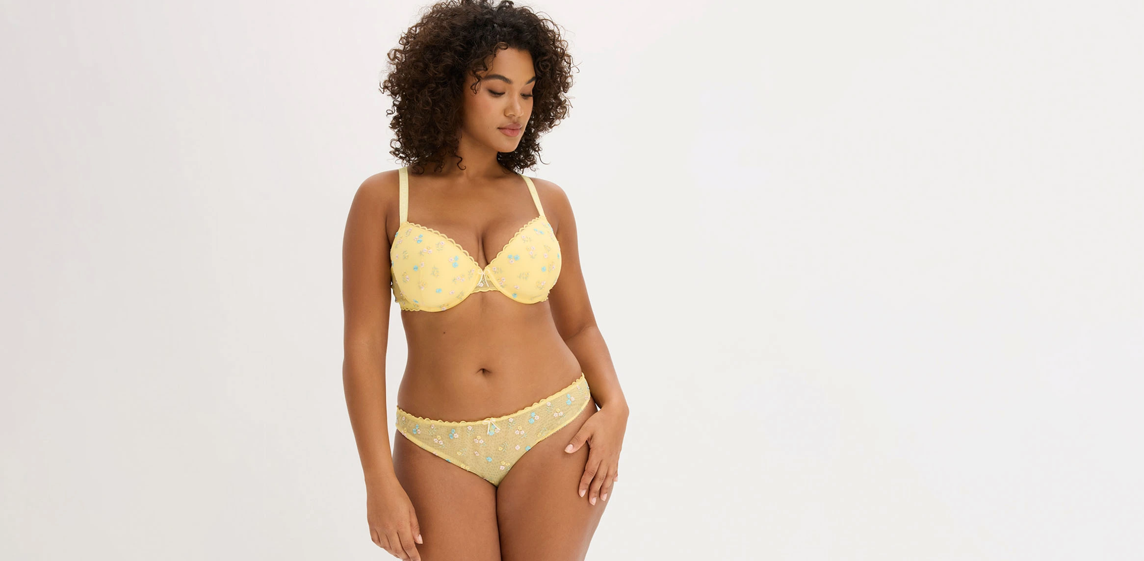 Femme vêtue d'une lingerie jaune à broderie florale.