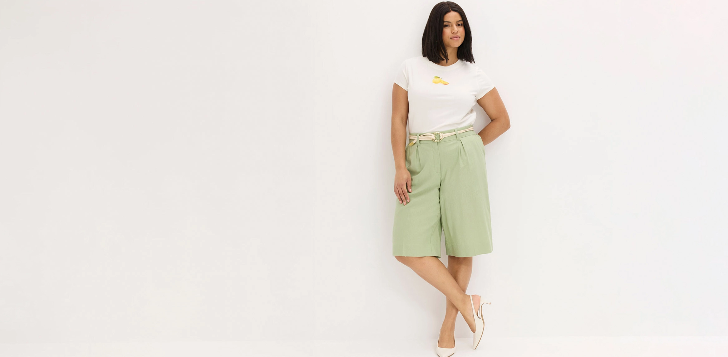 T-shirt blanc, bermuda vert menthe et sandales beige.