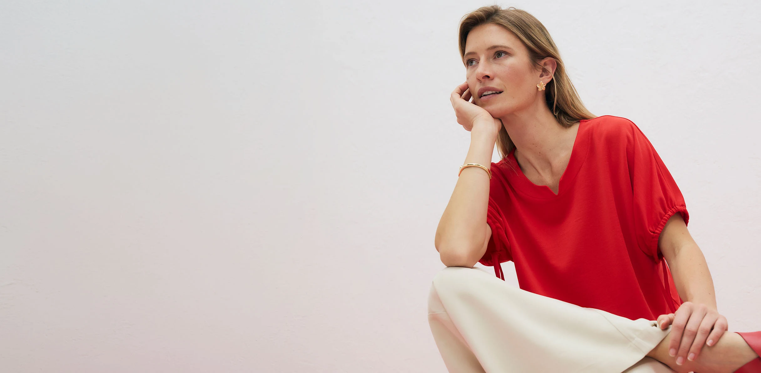T-shirt rouge élégant avec décolleté en V, associé à un pantalon de couleur claire.
