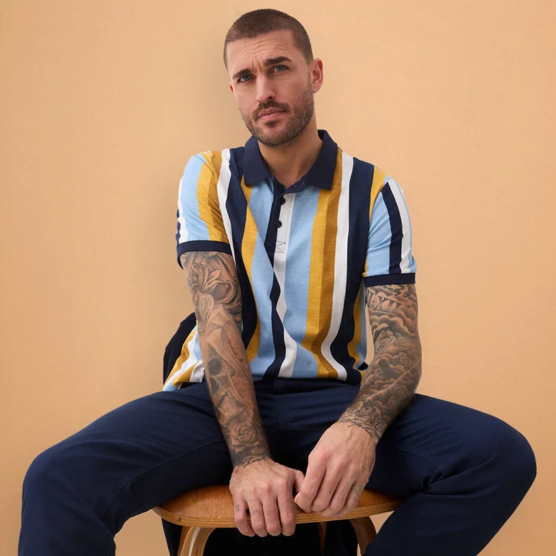 Polo rayé avec col bleu foncé, associé à un pantalon de couleur foncée.