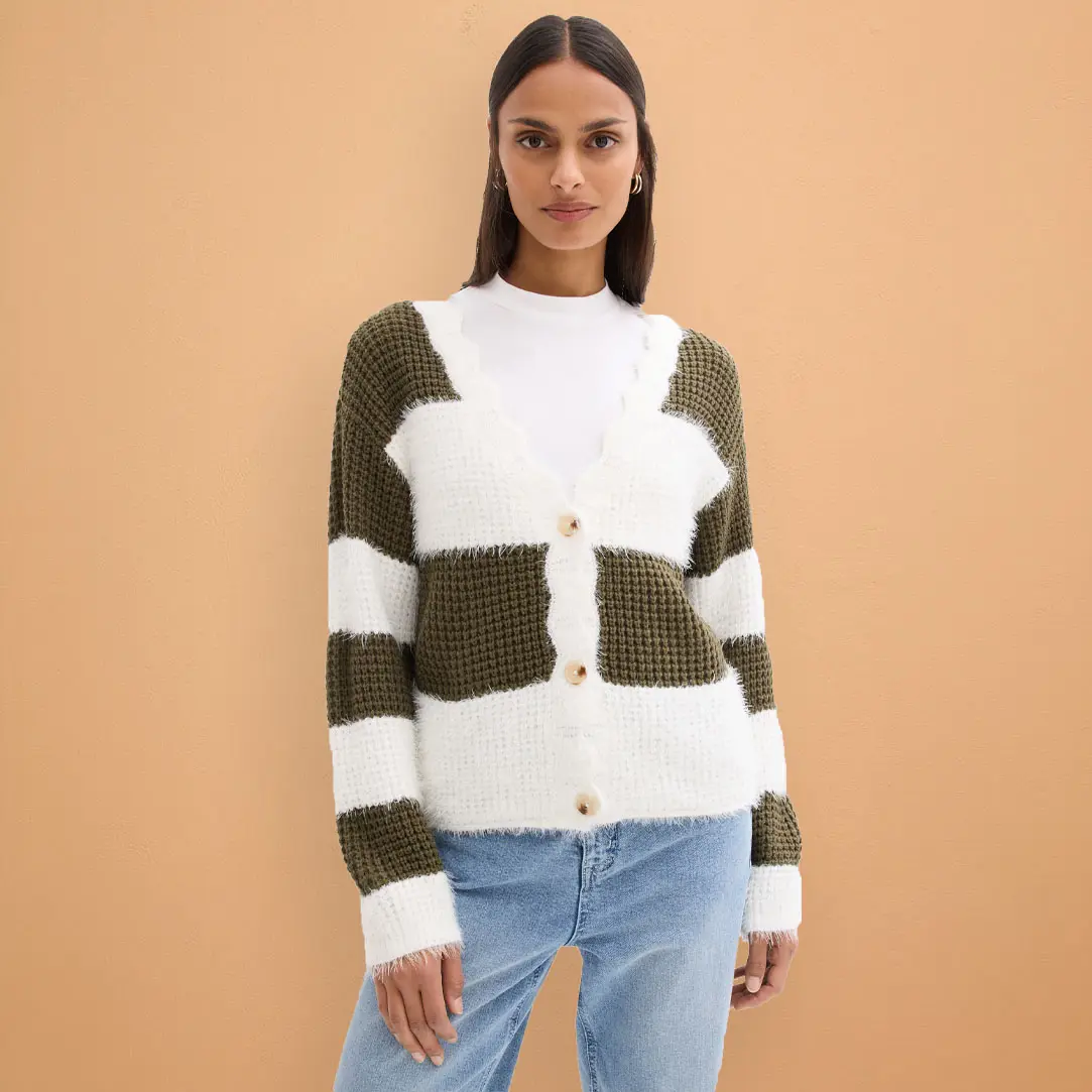 Cardigan en maille vert olive et blanc, associé à un jean bleu clair.